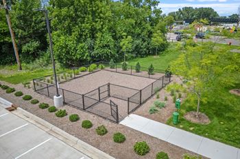 a fenced in tennis court in a park with trees
